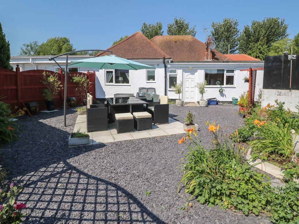 A garden with a table and chairs under an umbrella at Beachway in Holywell