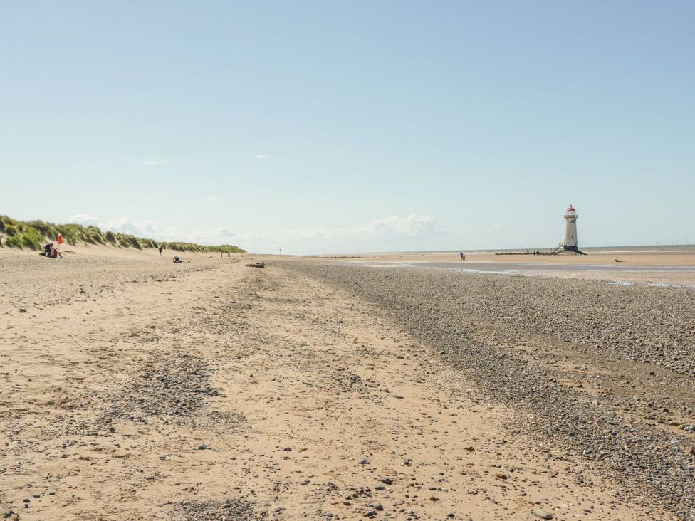 A beach with a lighthouse and people walking at Beachway in Holywell