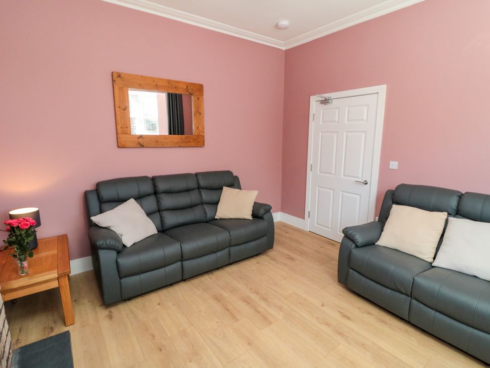 A living room with sofas, a mirror, and a door at Portobell House in Bridlington
