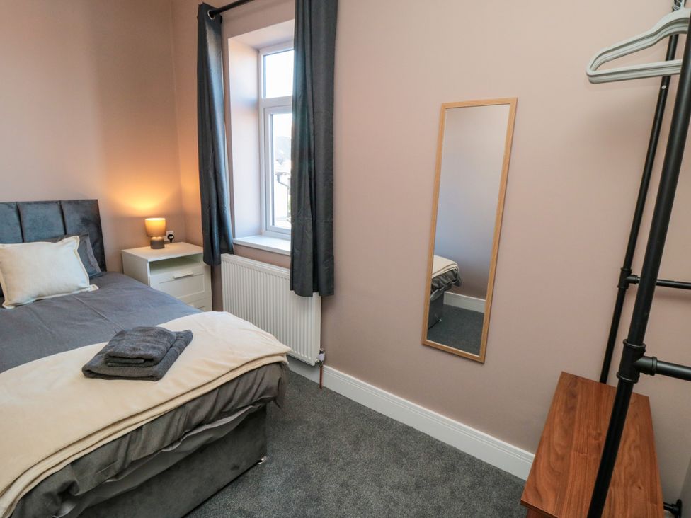 A bedroom with a bed, nightstand, lamp and mirror at Portobell House in Bridlington