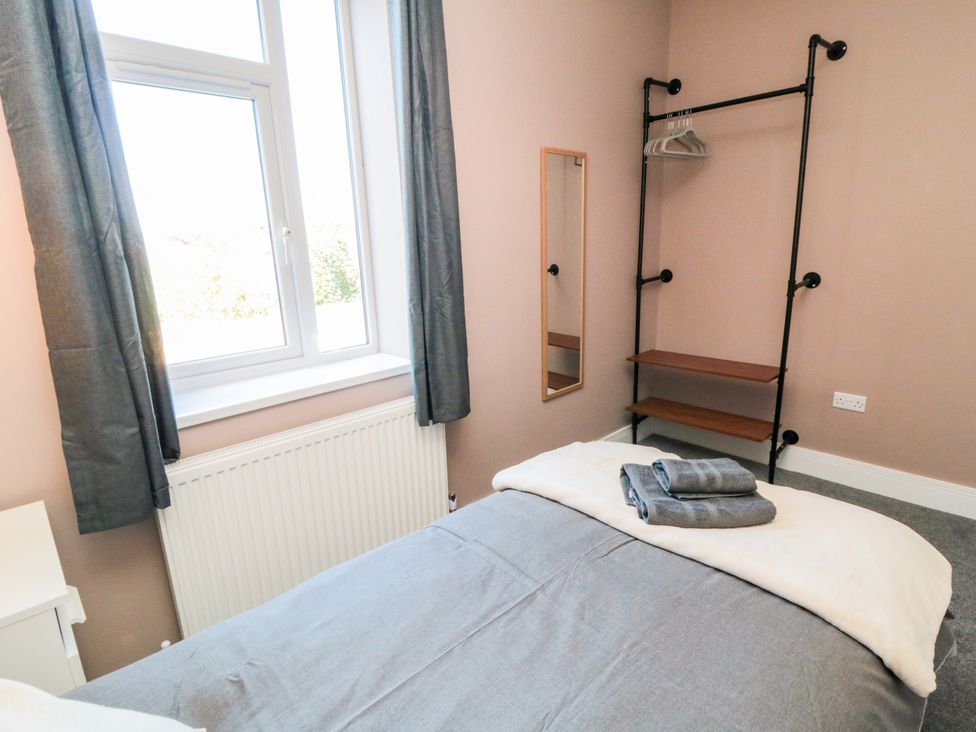 A bedroom with a bed, shelf, mirror, and window at Portobell House in Bridlington