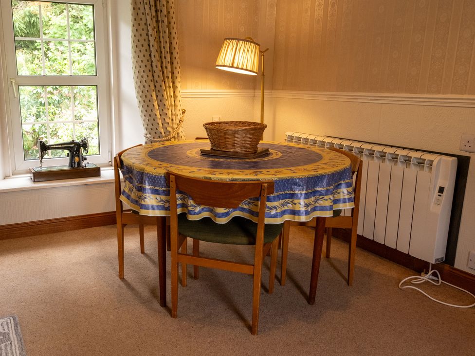 A table with chairs and a lamp at Curlew Cottage Crianlarich