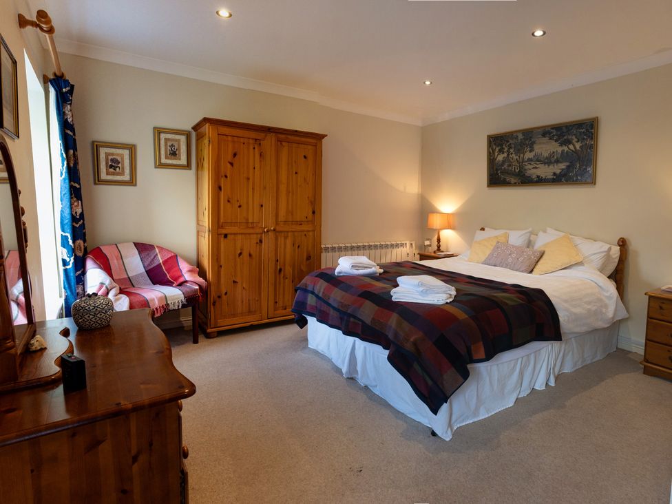 A bedroom with a bed and wardrobe at Curlew Cottage in Crianlarich
