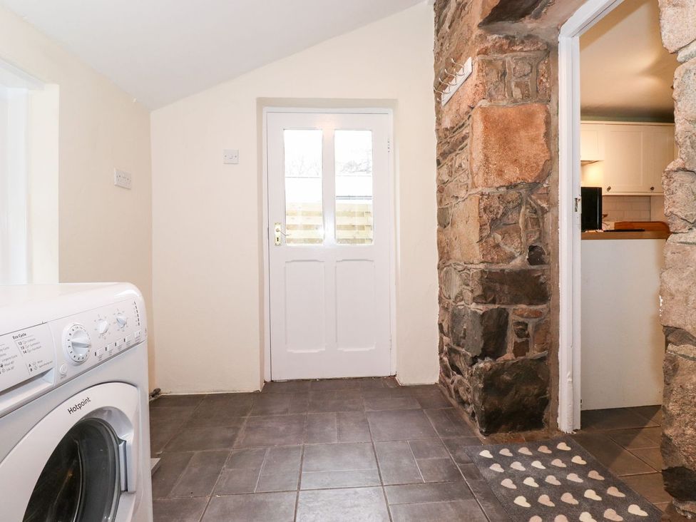A laundry room with a washing machine and stone wall at Irt Cottage Seascale