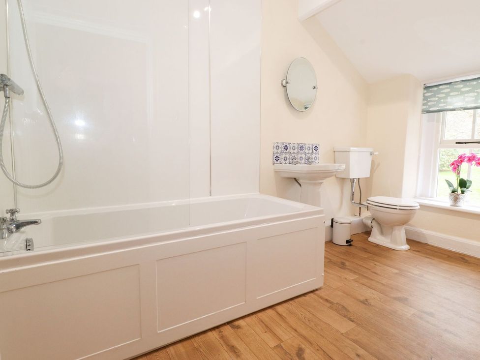 A bathroom with bathtub, toilet, sink and window at Irt Cottage in Seascale