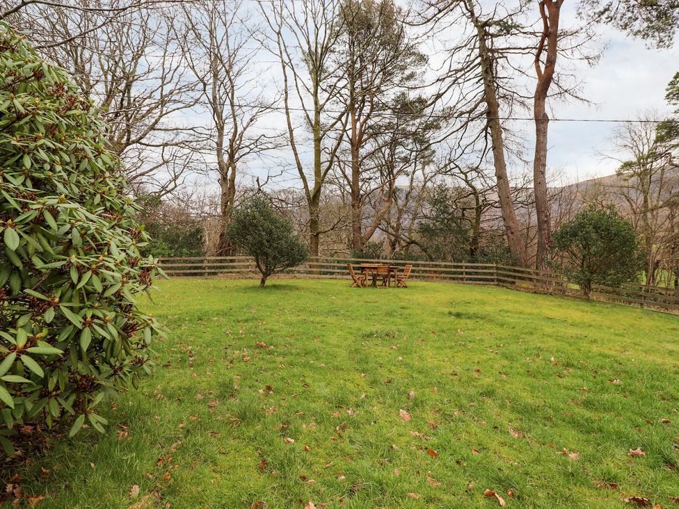 A garden with a table and chairs surrounded by trees at Irt Cottage Seascale