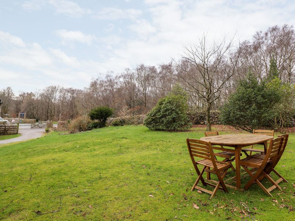 A garden with wooden table and chairs at Irt Cottage Seascale