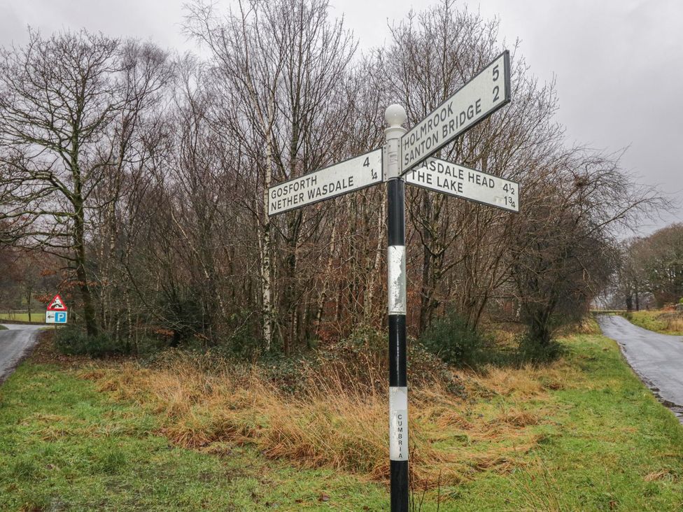 A road signpost with directions in a wooded area at Irt Cottage Seascale