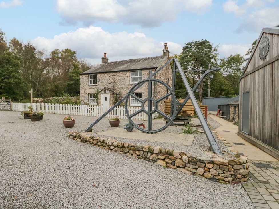 An outdoor area with a stone house and mechanical wheel at Irt Cottage in Seascale