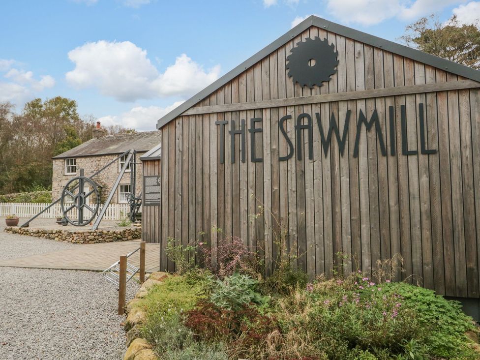 A sawmill building with a large wheel and outdoor area at The Sawmill in Seascale
