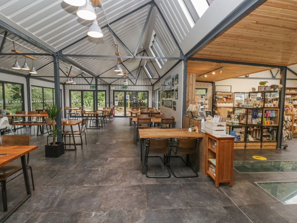 A café with tables and chairs and shelves containing various items at Irt Cottage in Seascale