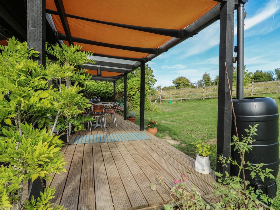 An outdoor area with a table and chairs under a cover at Orchard Lodge in Dover