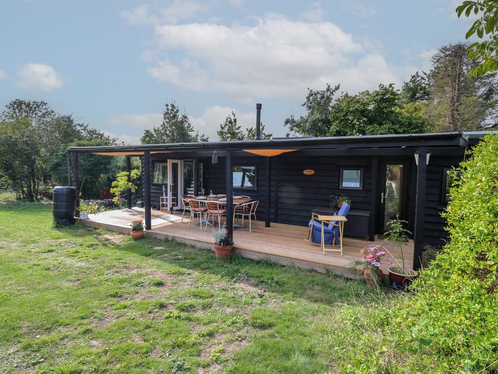 A wooden cabin with a deck and outdoor furniture at Orchard Lodge in Dover