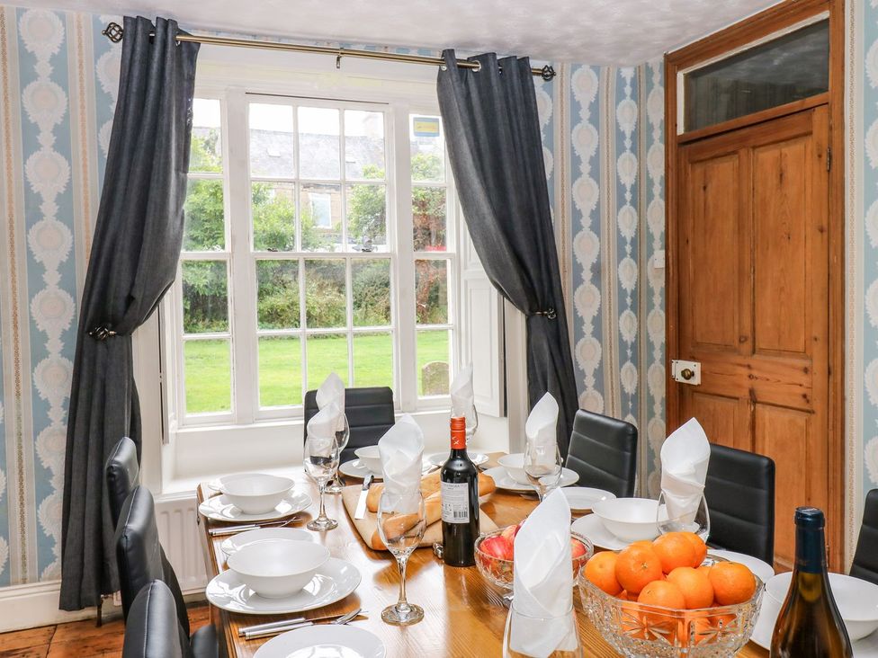 A dining room with a table set and a view outside at Prudhoe Cottage in Prudhoe