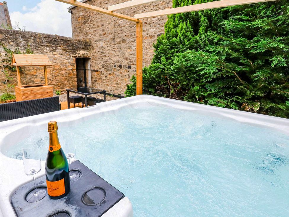 A hot tub with champagne and glasses at Prudhoe Cottage in Prudhoe