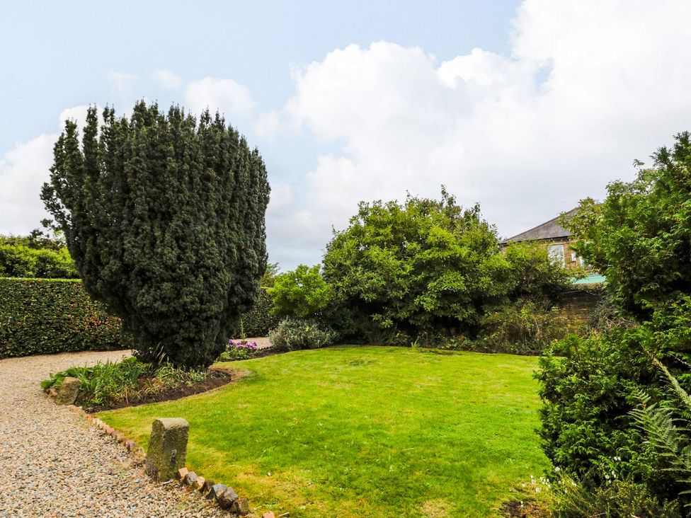 A garden with trees and grass at Prudhoe Cottage in Prudhoe