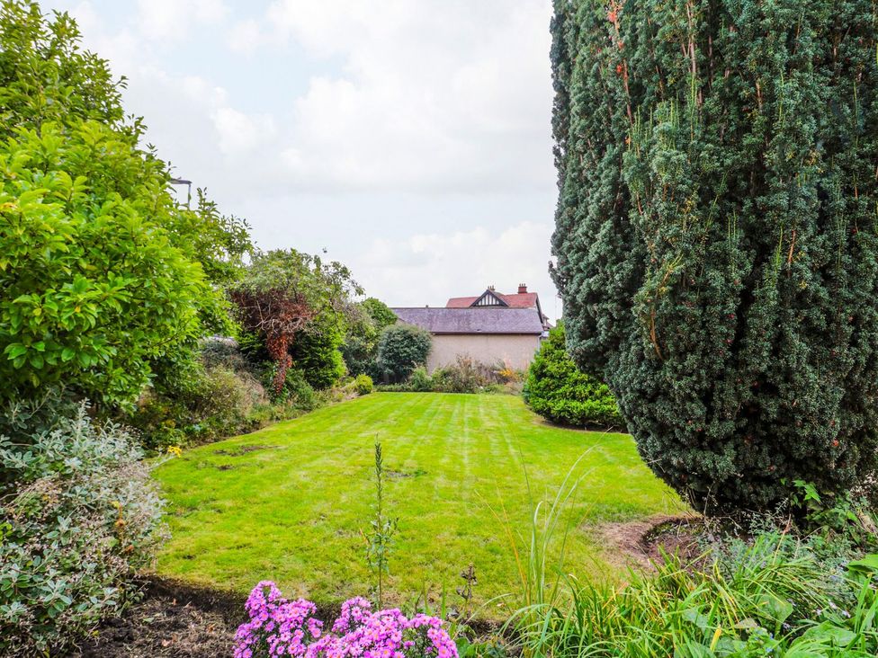 A garden with grass, flowers, and trees at Prudhoe Cottage in Prudhoe