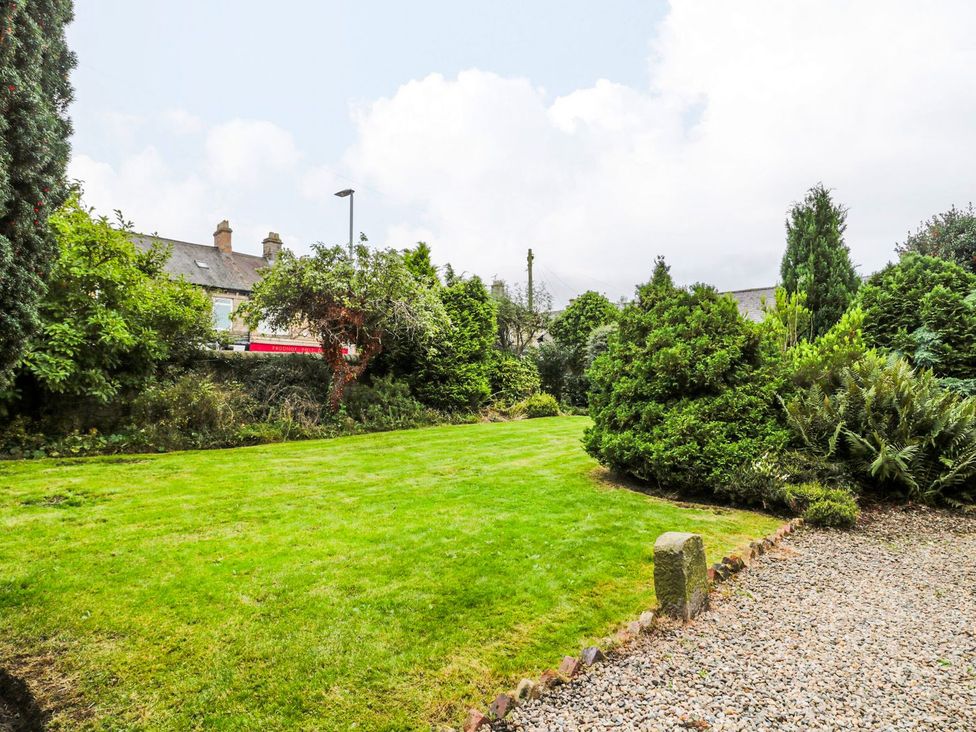 A garden with grass and trees at Prudhoe Cottage in Prudhoe