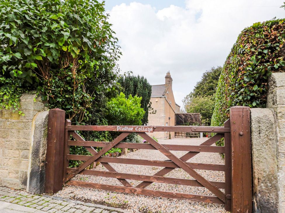 A gate leading to a gravel driveway at Prudhoe Cottage in Prudhoe