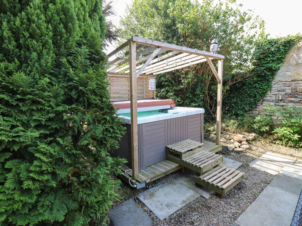 A hot tub on a wooden platform in a garden at Prudhoe Cottage in Prudhoe