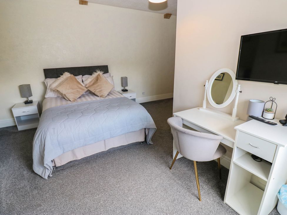 A bedroom with a bed, bedside tables, desk and television at Prudhoe Cottage in Prudhoe