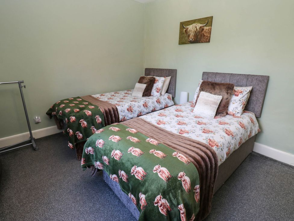 A bedroom with two beds and a clothes rack at Prudhoe Cottage in Prudhoe