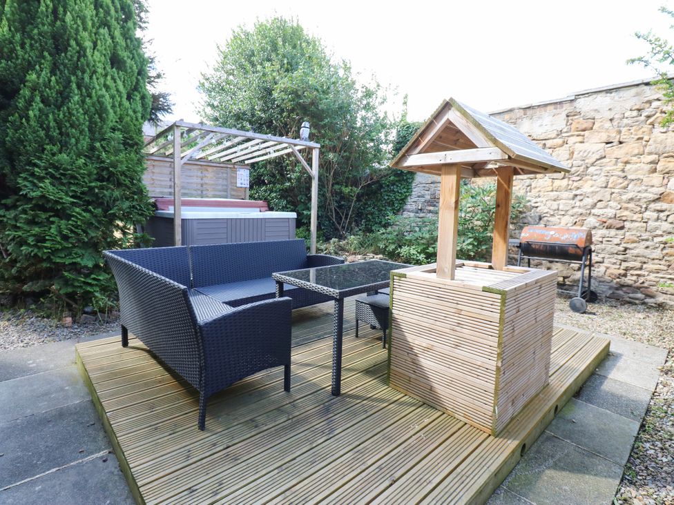 A garden with a sofa, table, hot tub, and barbecue grill at Prudhoe Cottage in Prudhoe