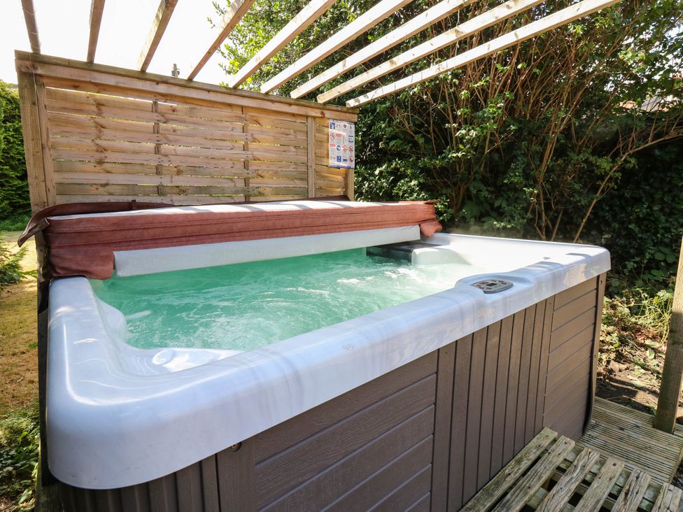 A hot tub with water and a wooden pergola at Prudhoe Cottage in Prudhoe