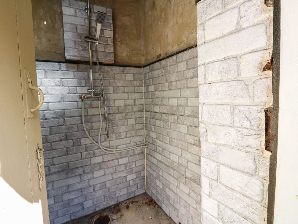 A bathroom with a shower and tiled walls at Prudhoe Cottage in Prudhoe
