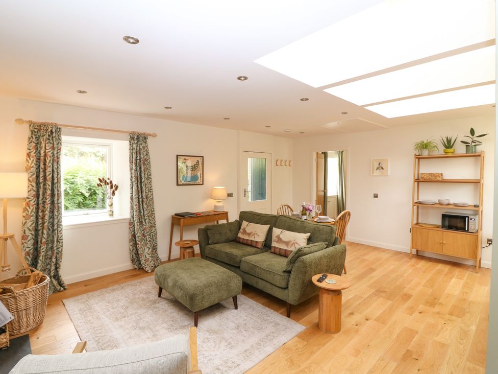 A living room with a sofa and a table at Doocot Wood Cottage in Forfar