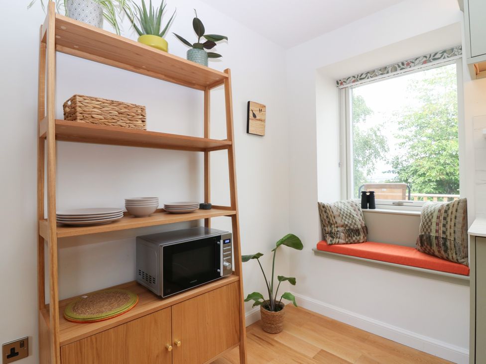 A kitchen with shelving, microwave, and seating at Doocot Wood Cottage Forfar