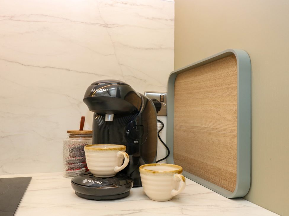 A coffee machine with two cups on a kitchen counter at Doo'cot Wood Cottage in Forfar