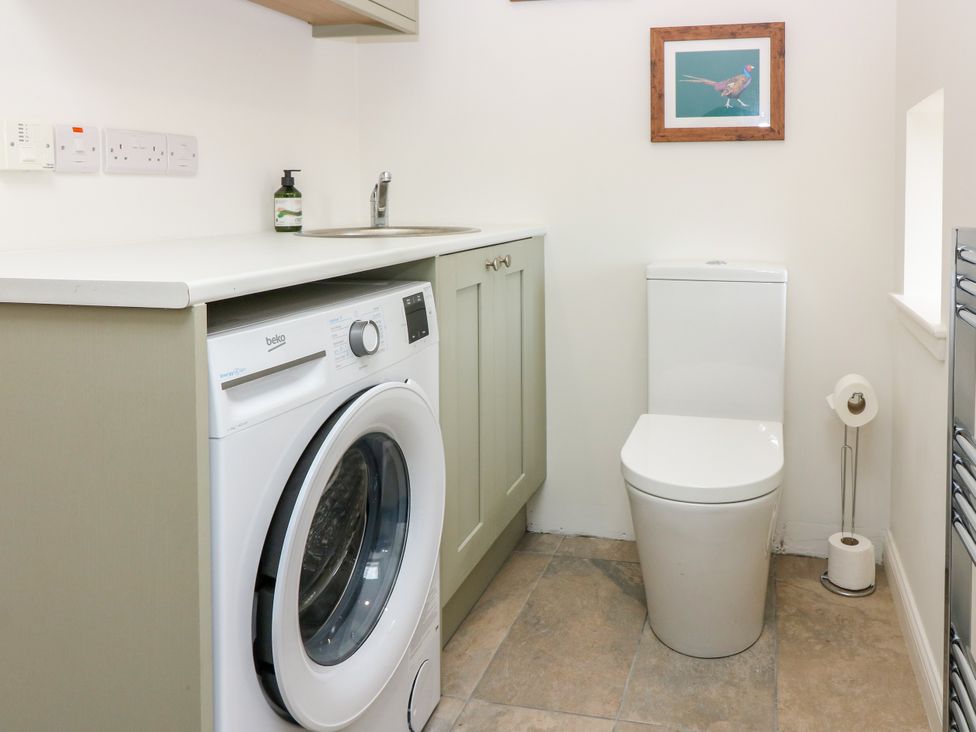 A laundry room with a washing machine and toilet at Doo'cot Wood Cottage Forfar
