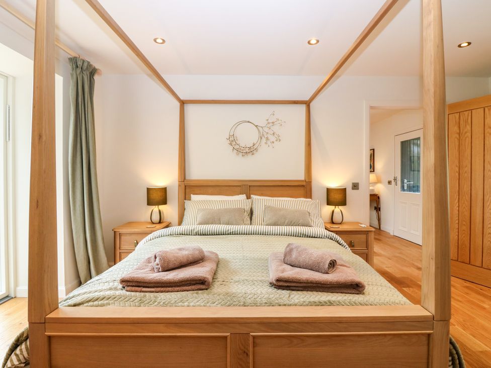 A bedroom with a four-poster bed and nightstands at Doo'cot Wood Cottage in Forfar