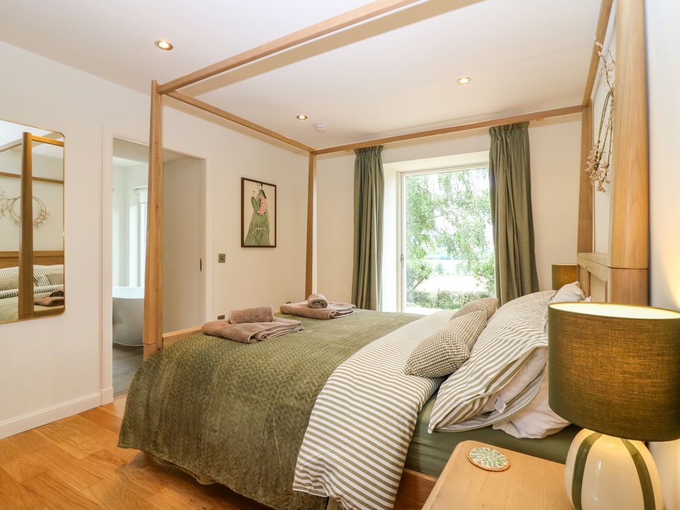 A bedroom with a bed and a mirror at Doocot Wood Cottage in Forfar