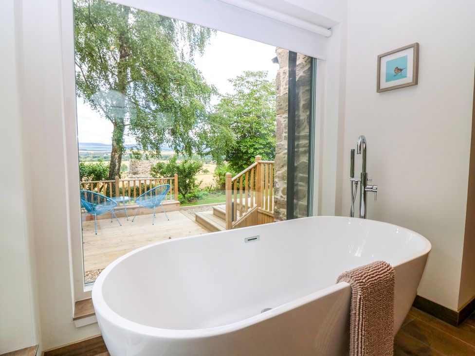 A bathroom featuring a bathtub with a view at Doo'cot Wood Cottage in Forfar
