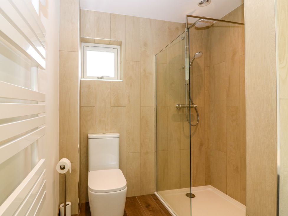 A bathroom featuring a shower and toilet at Doo'cot Wood Cottage in Forfar