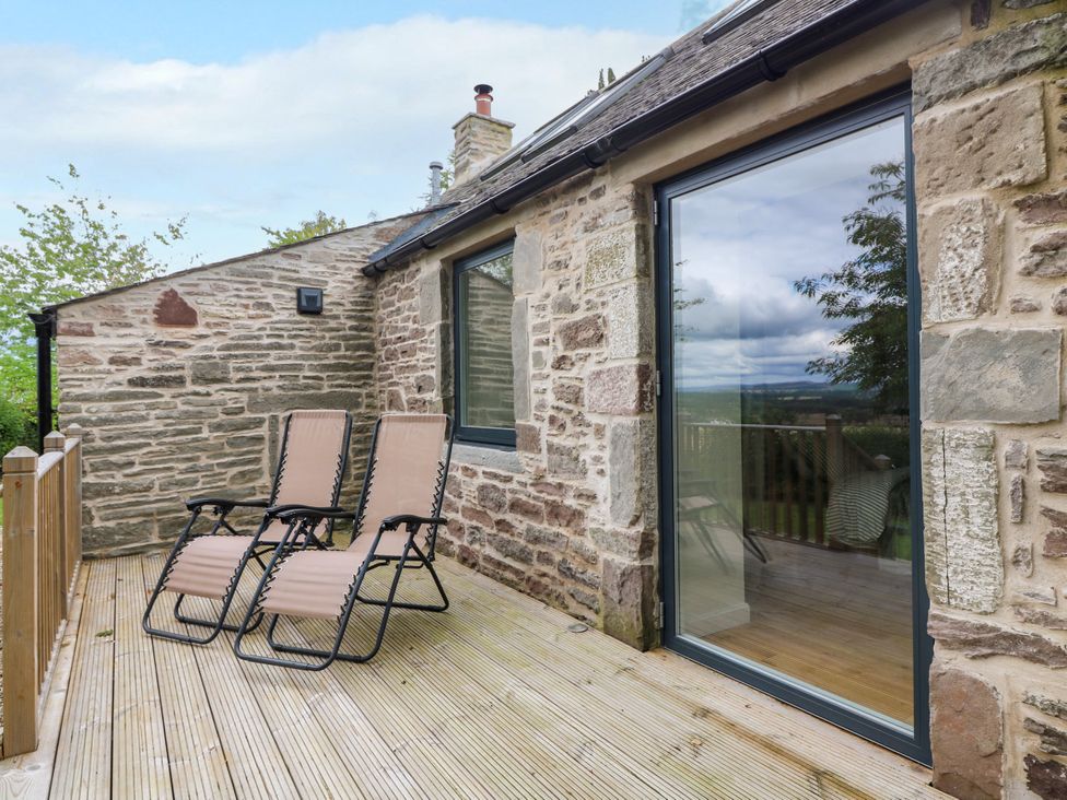 An outdoor area with chairs and a sliding door at Doocot Wood Cottage in Forfar