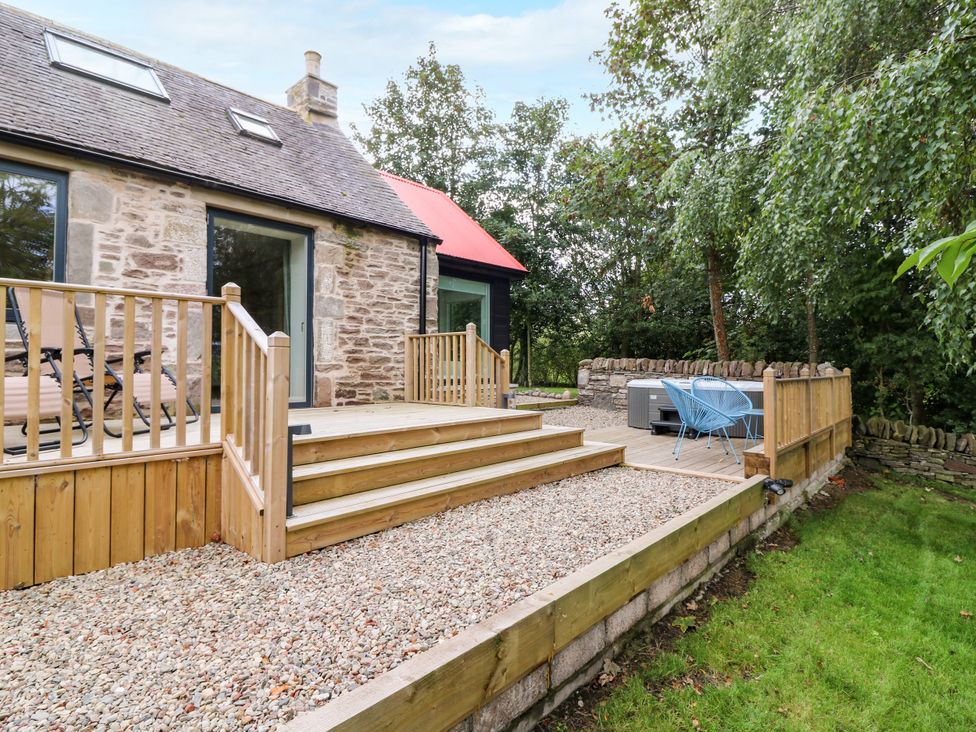 An outdoor deck area with gravel and a hot tub at Doocot Wood Cottage Forfar