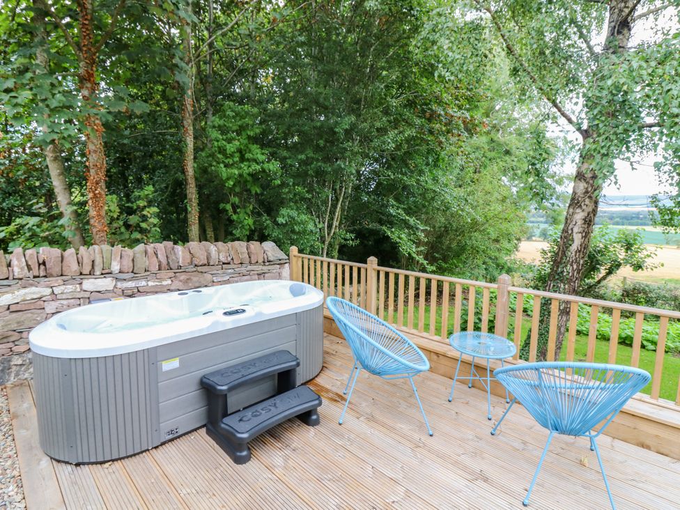 An outdoor area with a hot tub and seating at Doo'cot Wood Cottage in Forfar