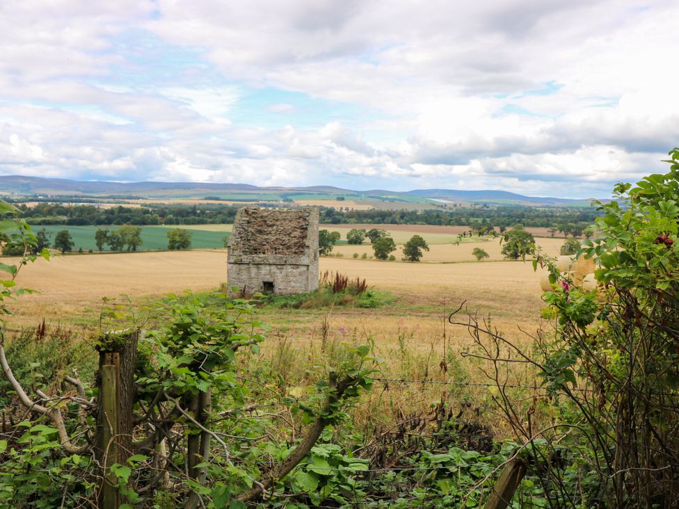A ruin in a field with mountains and sky at Doocot Wood Cottage Forfar