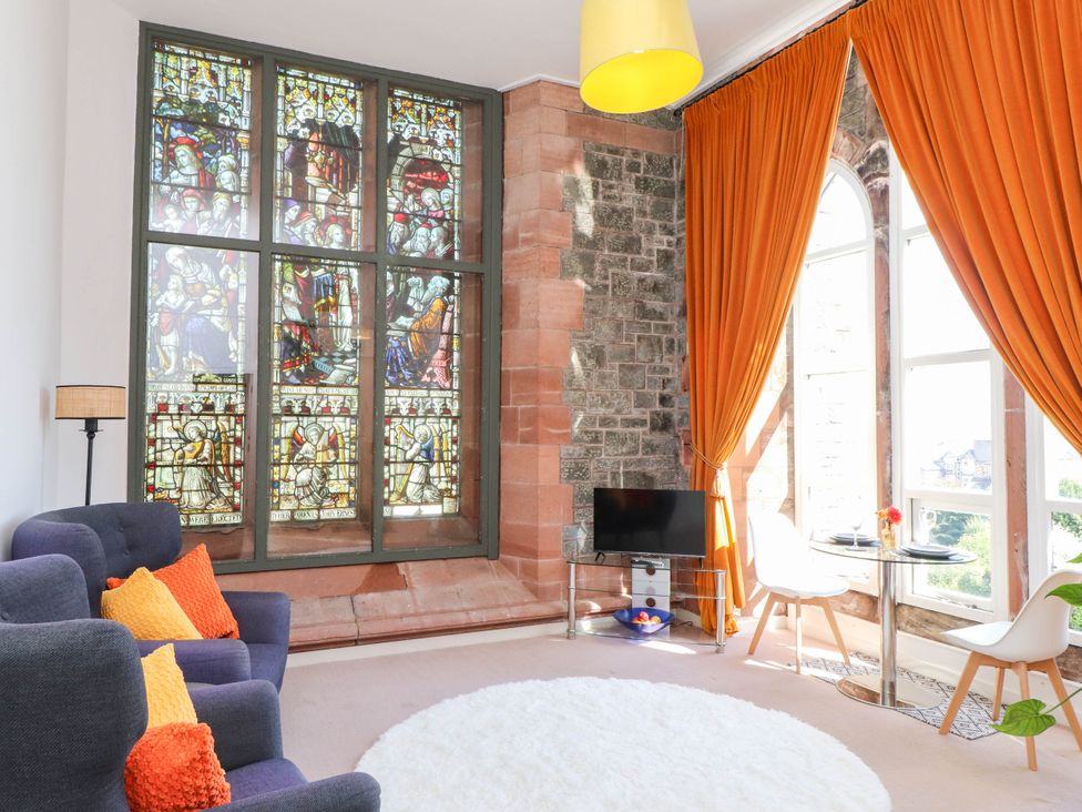 A living room with a stained glass window and sofa at Flat 16 in Criccieth