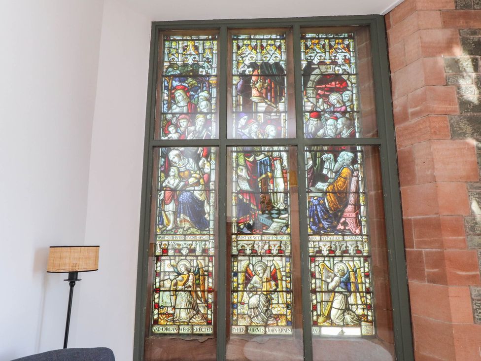A stained glass window with various figures at Flat 16 in Criccieth
