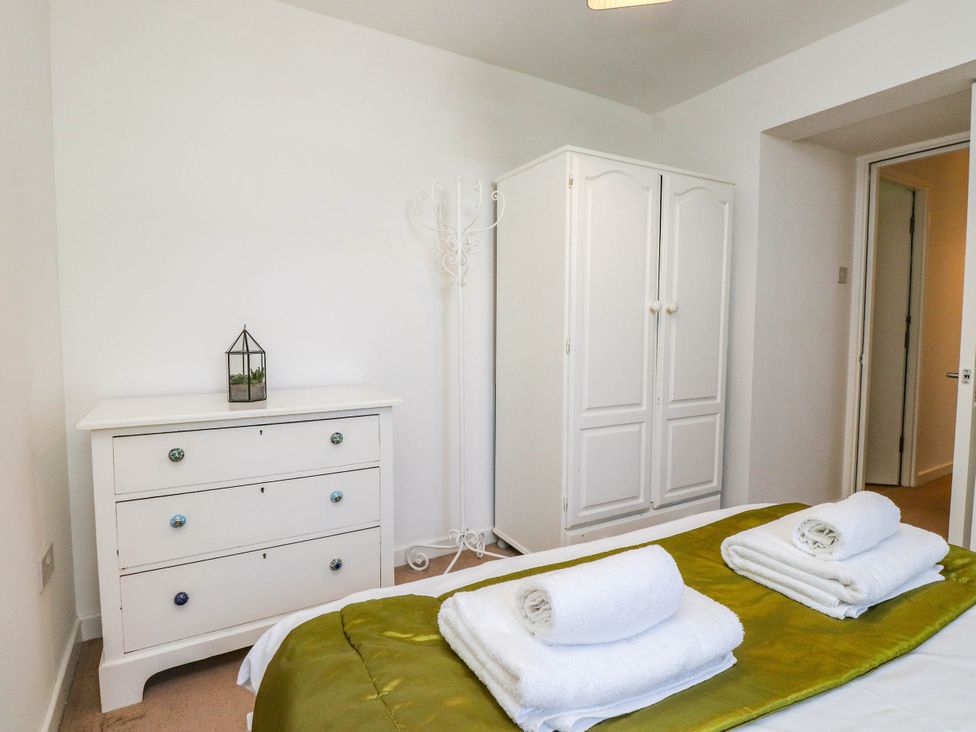 A bedroom with a bed and dresser at Flat 16 in Criccieth