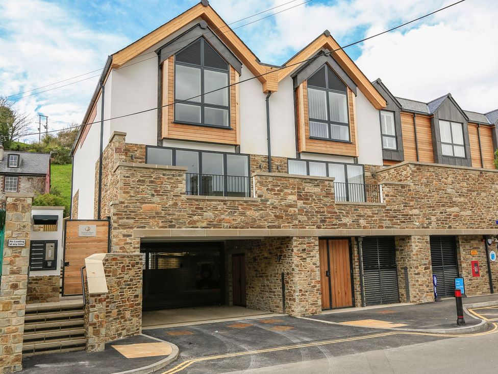 A modern building with multiple windows and a parking area at Beachstone in Salcombe