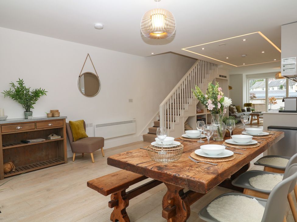 A dining room with a wooden table set for dinner at Beachstone in Salcombe