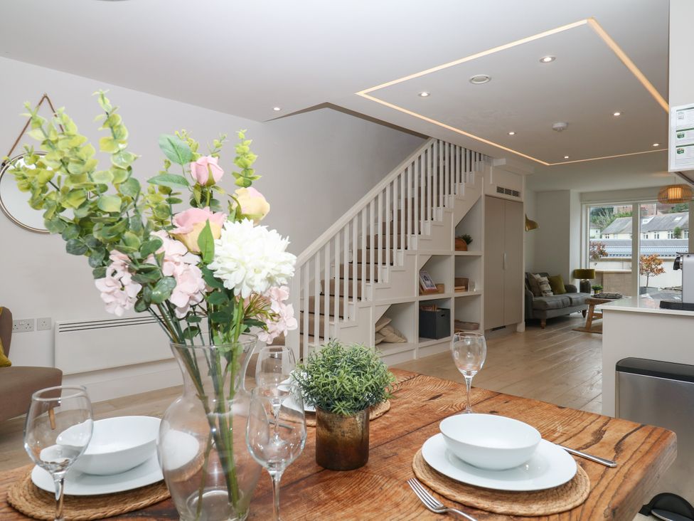 A living room with a dining table and staircase at Beachstone in Salcombe