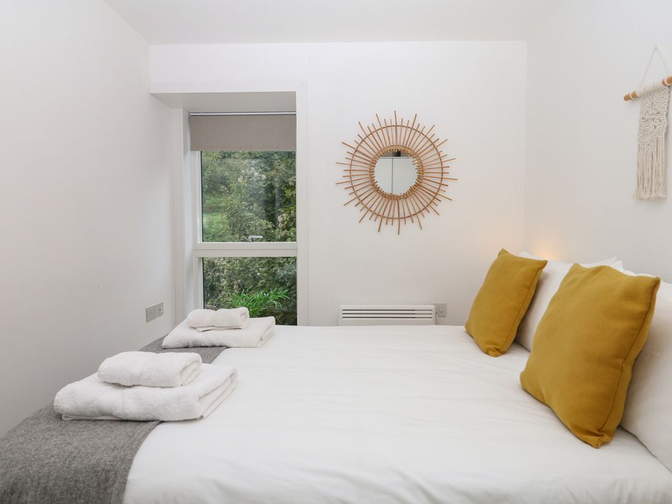 A bedroom with a bed and mirror at Beachstone in Salcombe