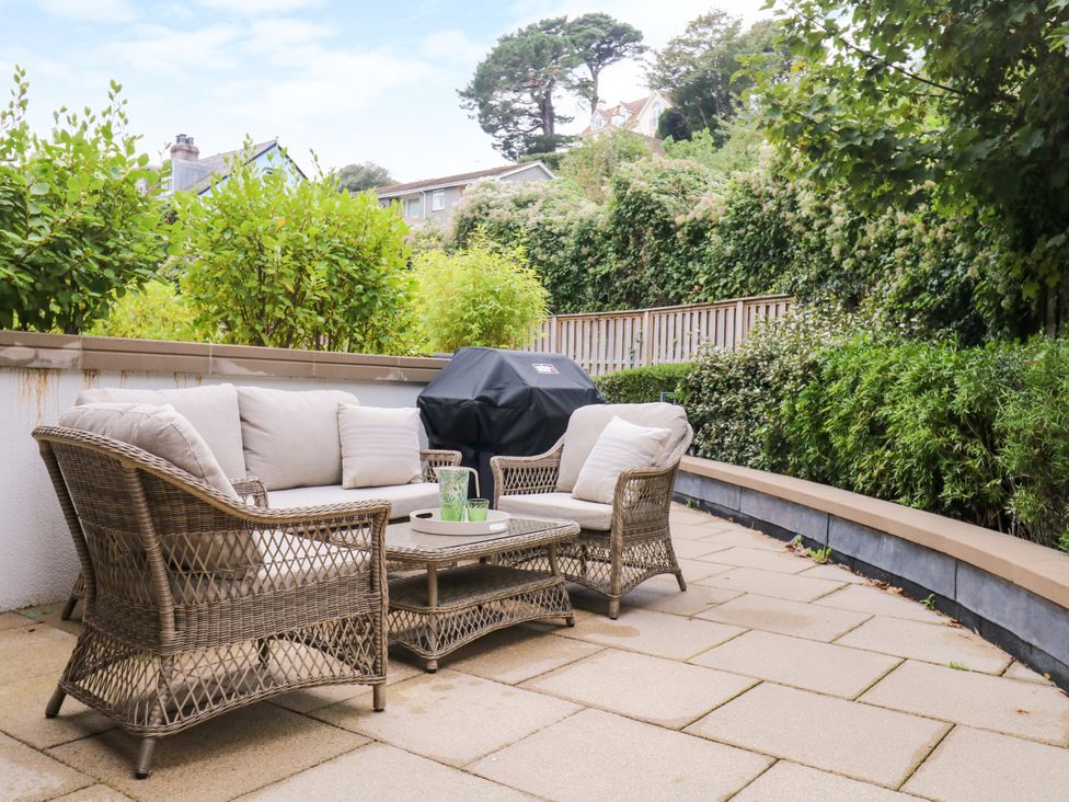 A garden with seating and a grill at Beachstone in Salcombe