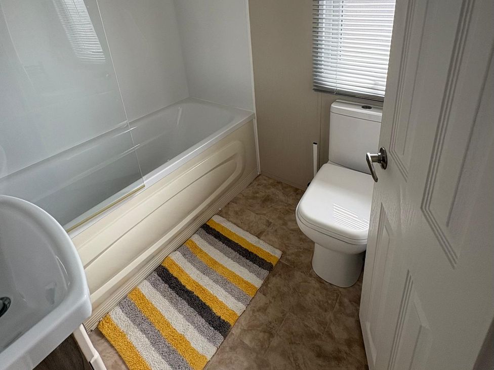 A bathroom with a bathtub, toilet, and sink at Lyons Robin Hood, Rhyl